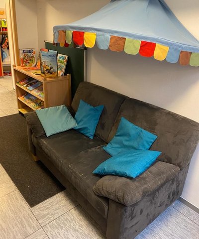 Dunkelgraues Sofa mit blauen Kissen und Zeltdach oben drüber